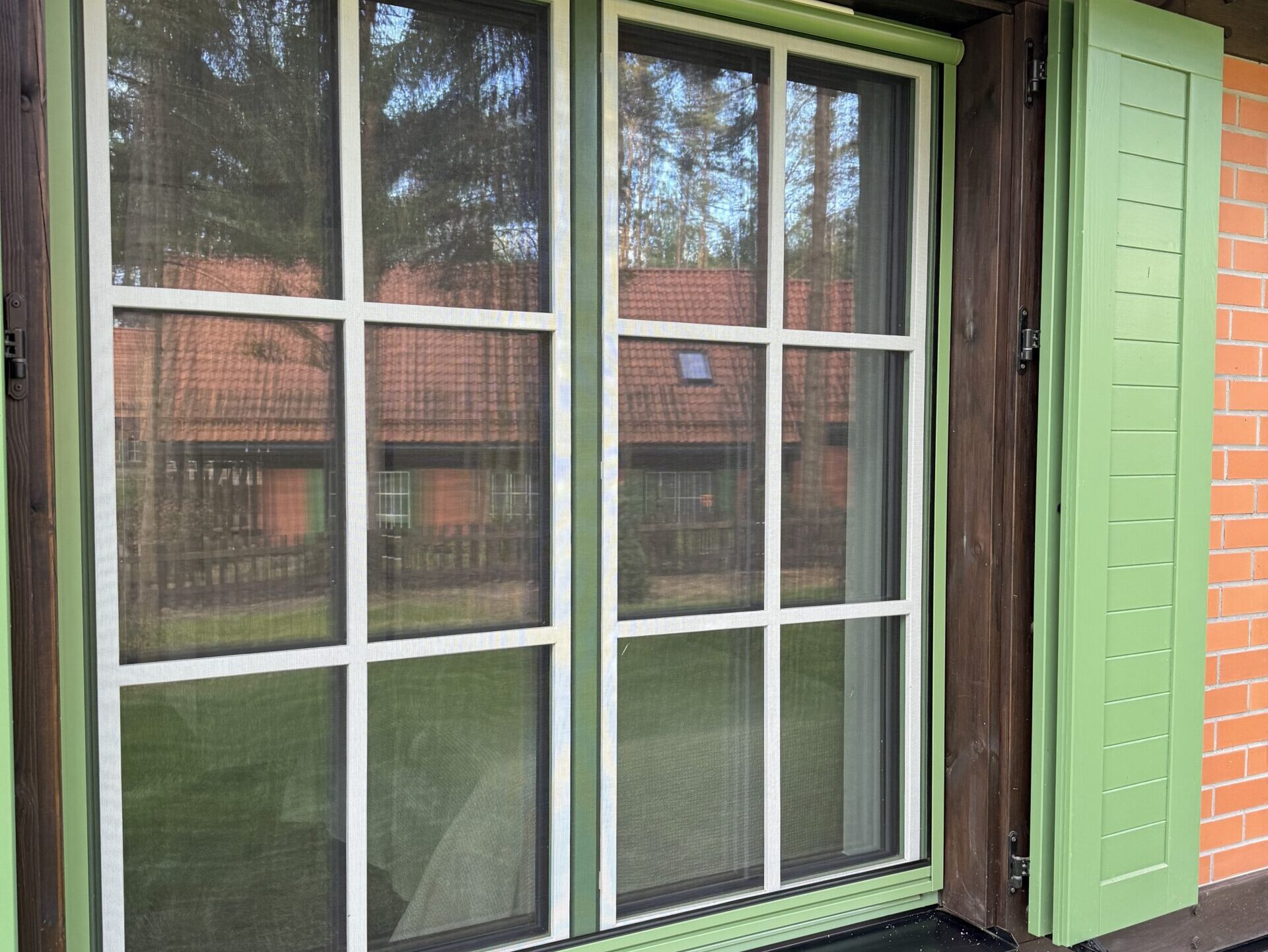 Moskitiery w zielonych okiennicach – dyskretna ochrona w eleganckiej oprawie